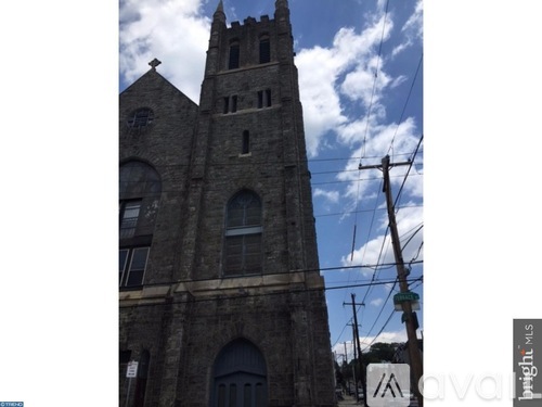 A church steeple is seen against a blue sky with clouds.