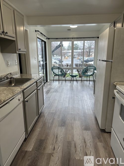 A kitchen with white appliances and wooden floors.