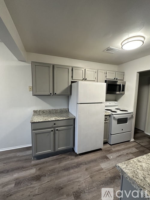 A kitchen with a white refrigerator, microwave, and stove.