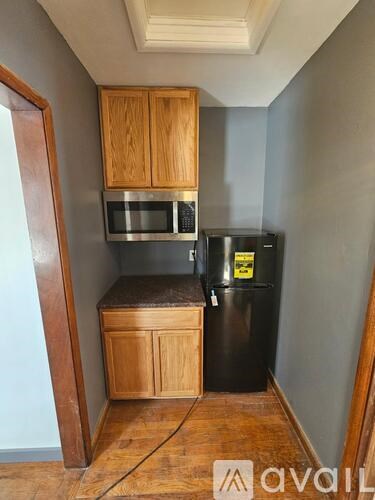 A kitchen with wooden cabinets and a black fridge.