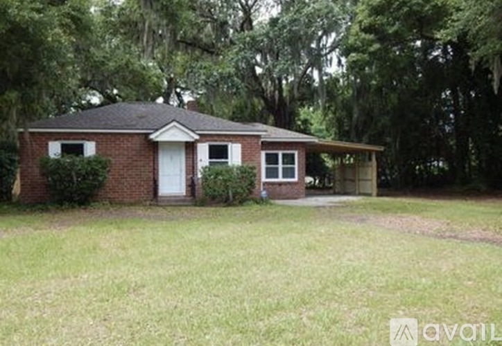 A small house with a white door and windows is surrounded by greenery.