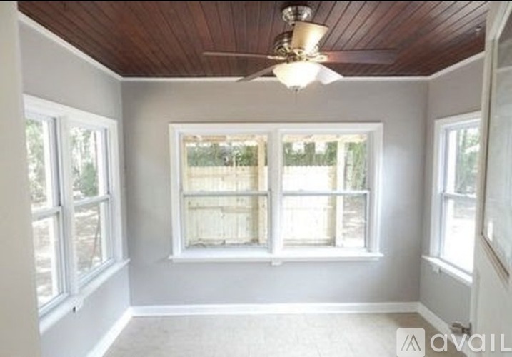 A room with a wooden ceiling and a window with a view of a fence.