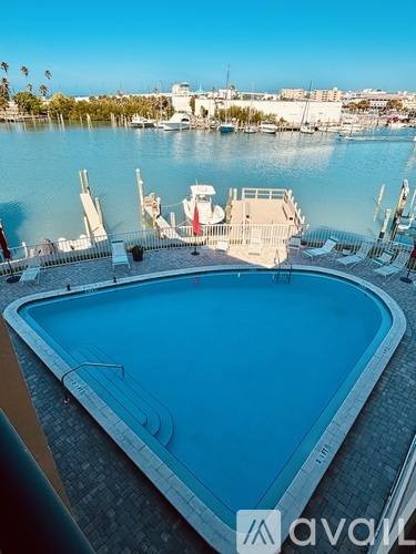 A large swimming pool with a view of the water and boats.