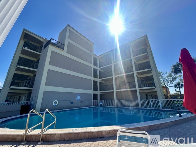 A sunny day at the poolside of a multi-story apartment building.
