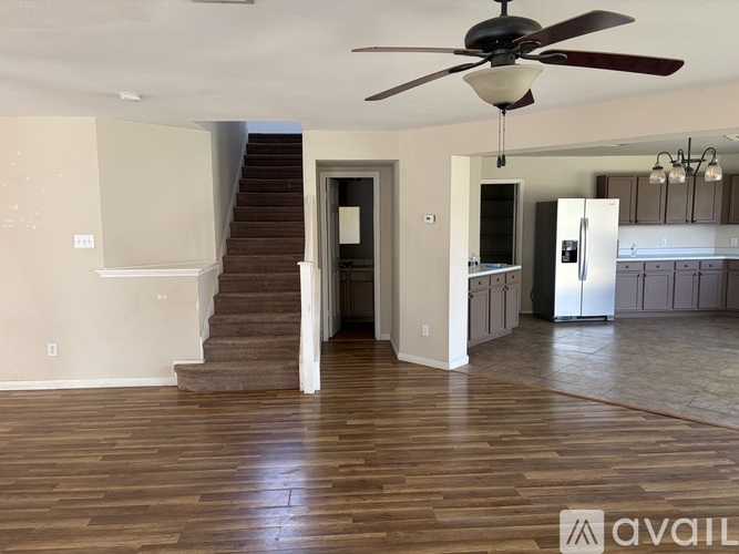 A living room with a staircase and a kitchen in the background.