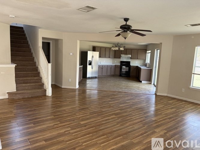 A spacious living room with hardwood floors and a staircase leading to the upper level.