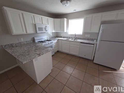 A kitchen with white cabinets and appliances.