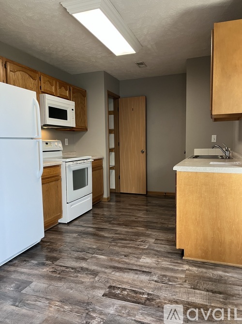A kitchen with a white refrigerator, wooden cabinets, and a white countertop.