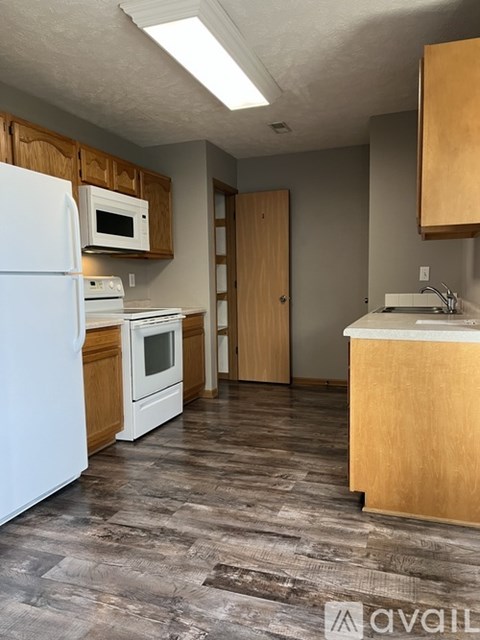 A kitchen with a white refrigerator, wooden cabinets, and a white countertop.