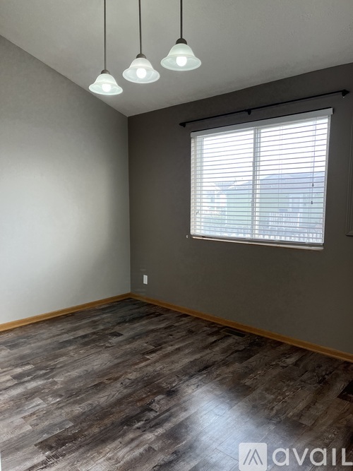 A room with wooden flooring and a window with blinds.