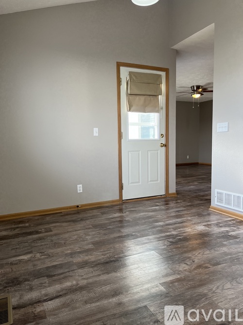 A room with a white door and wooden flooring.