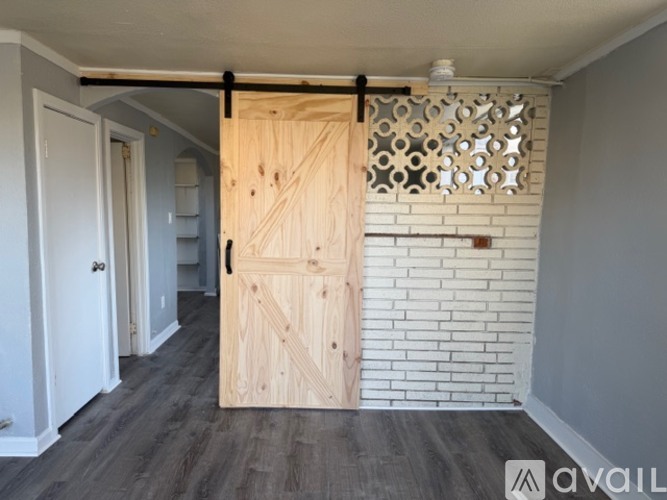 A room with a wooden door and a brick wall.