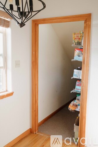 A small pantry with a wooden door and a chandelier above it.