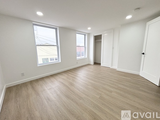 A spacious room with wooden flooring and white walls.