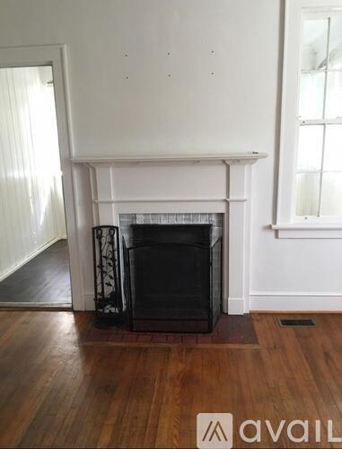 A black fireplace in a room with wooden floors and white walls.