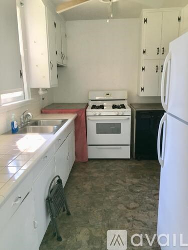 A kitchen with white cabinets and a white refrigerator.