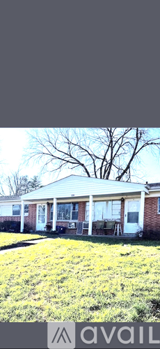 A house with a porch and a tree in the background.