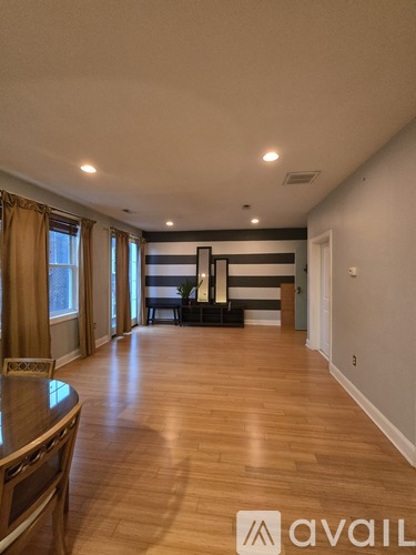 A living room with a wooden floor and a black and white striped couch.