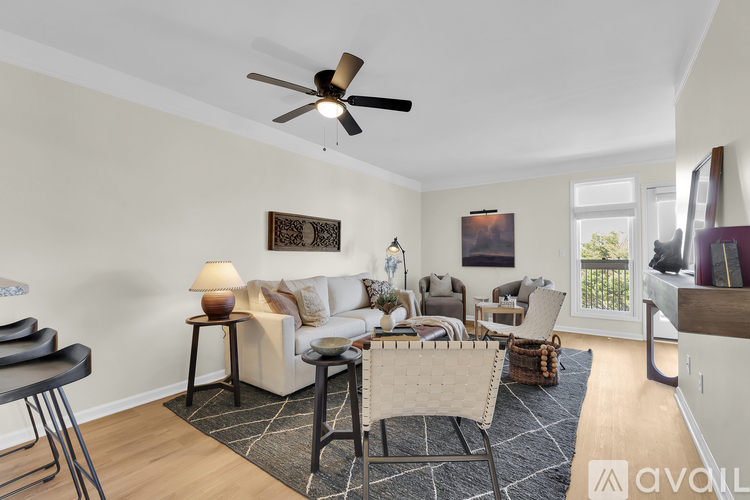 A living room with a white couch, a black rug, and a ceiling fan.