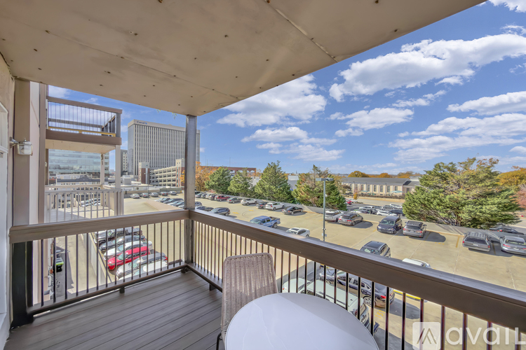 A balcony with a view of a parking lot and buildings.
