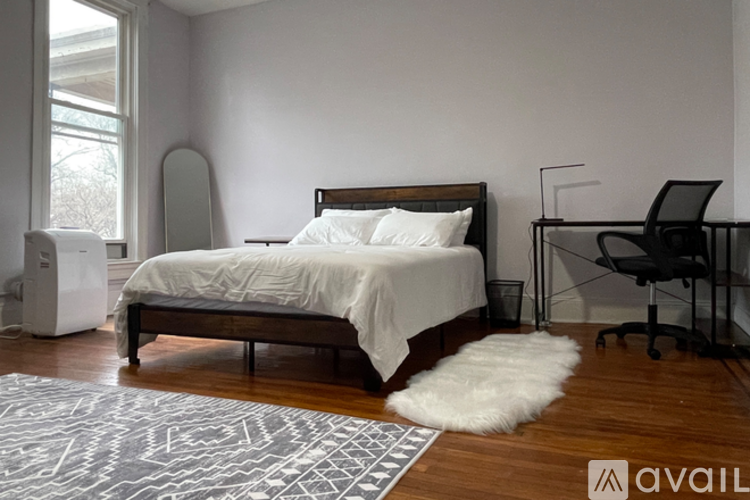A bedroom with a bed, chair, and a rug.