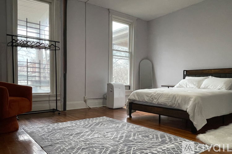 A bedroom with a bed, chair, and window.
