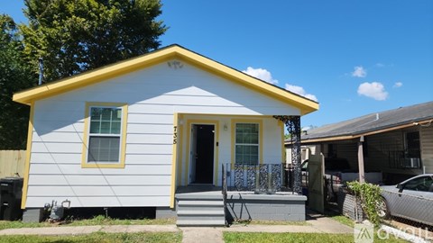 A small white house with a yellow roof and a grey front porch.