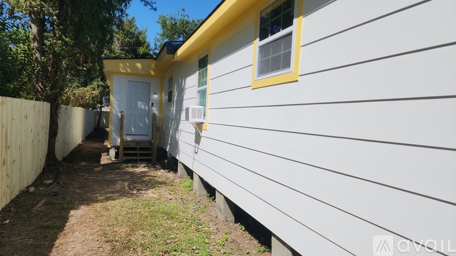 A white house with a yellow trim and a small porch.