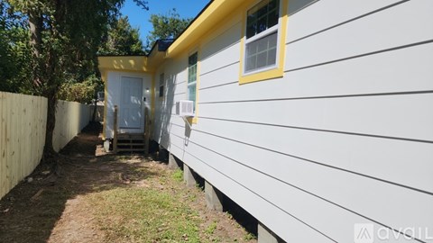 A white house with a yellow trim and a small porch.