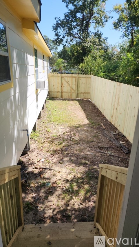A backyard with a wooden fence and a grassy area.