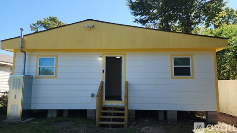 A small white house with a yellow roof and a black door.