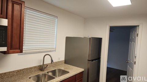 A kitchen with a sink, refrigerator, and cabinets.