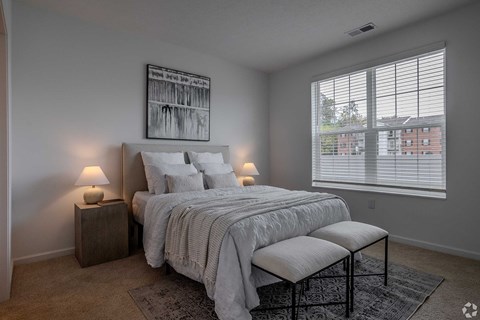 A bedroom with a large bed and a window with blinds.