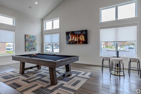 A room with a pool table and a painting of a fireplace on the wall.