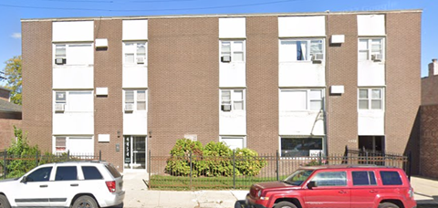 A red SUV is parked in front of a brick building.