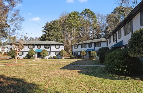 A row of houses with green trees in front.