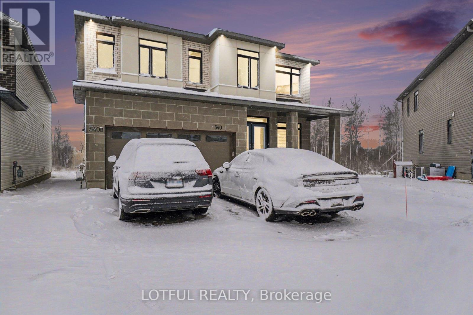 Two cars are parked in front of a house in the snow.