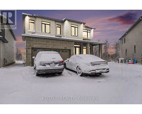 Two cars are parked in front of a house in the snow.