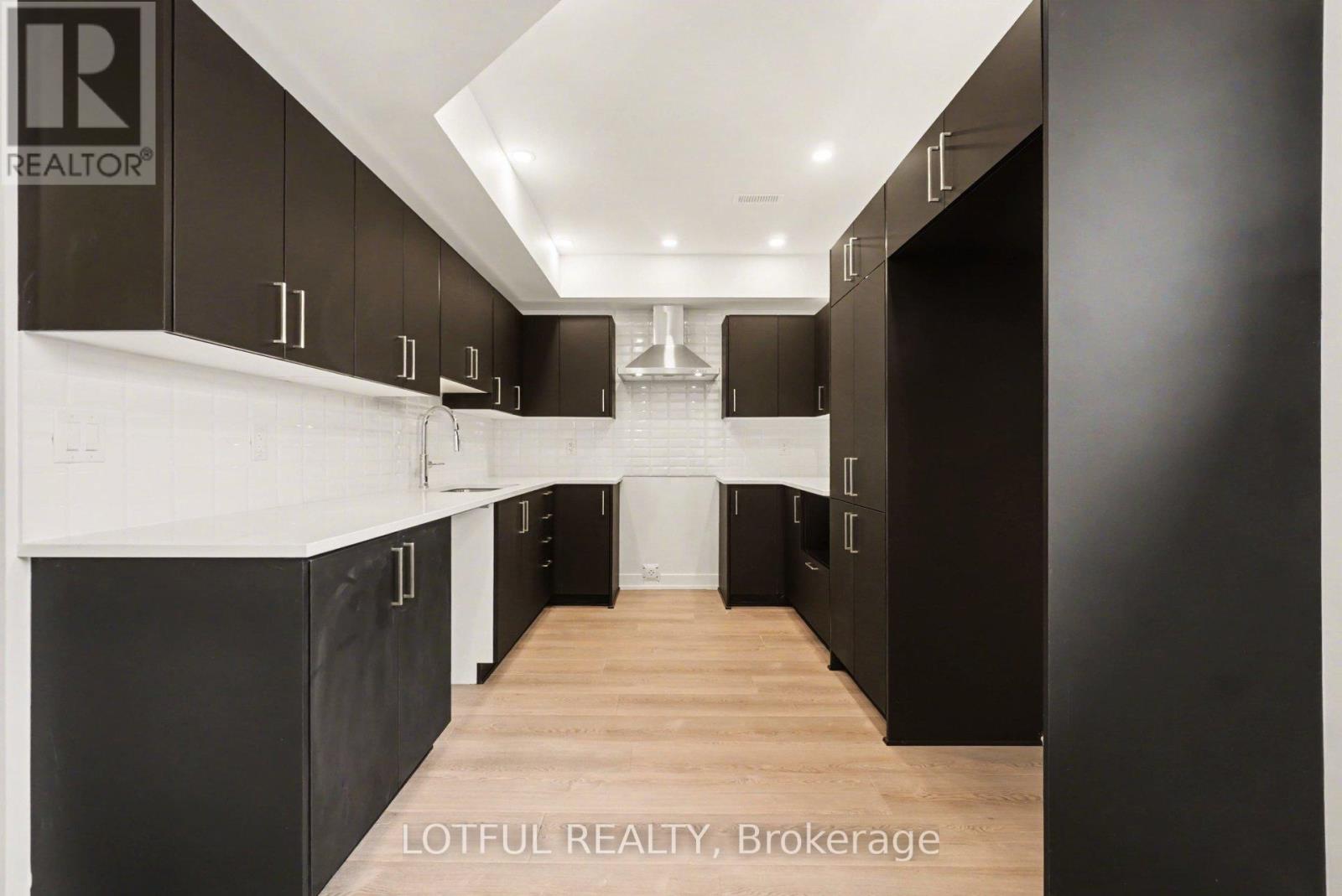 A modern kitchen with black cabinets and a white countertop.