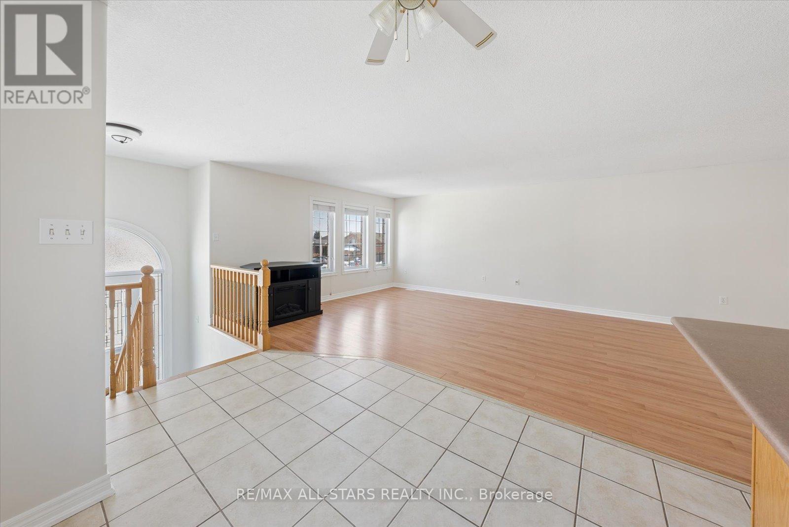 A spacious living room with a fireplace and a ceiling fan.