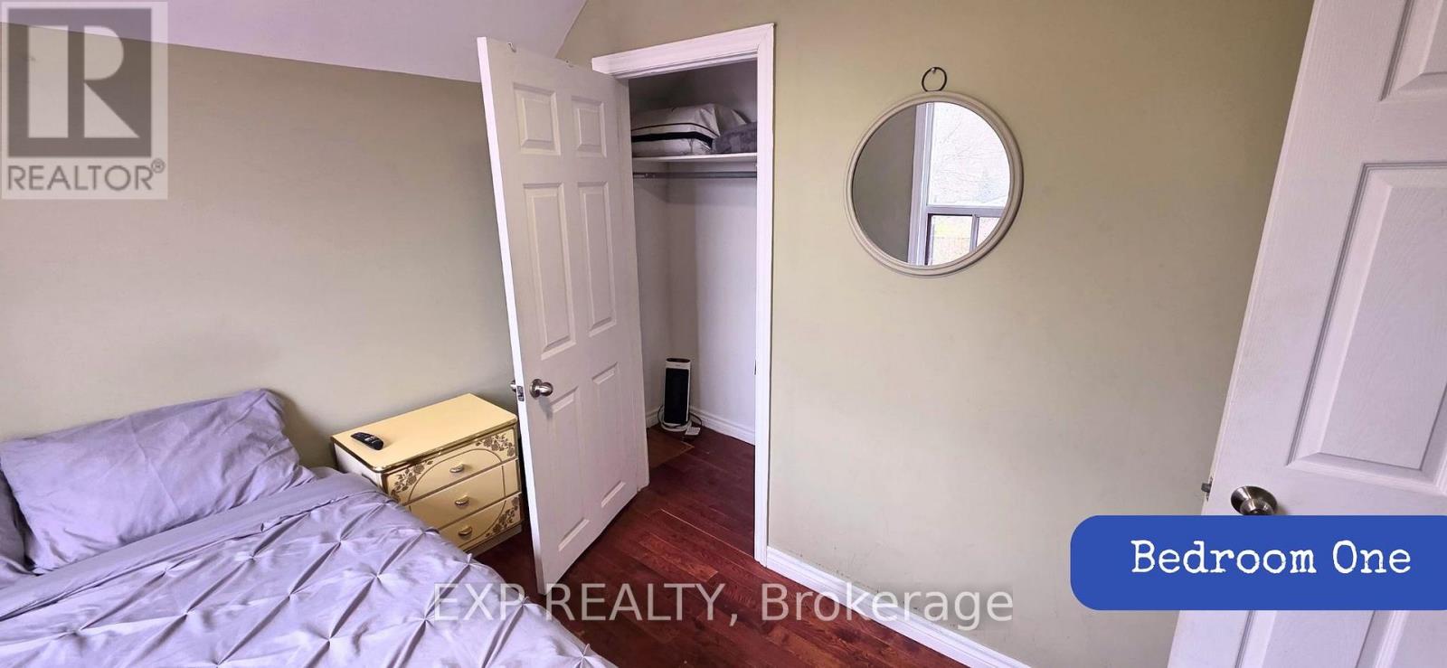 Bedroom one has a bed and a mirror on the wall.
