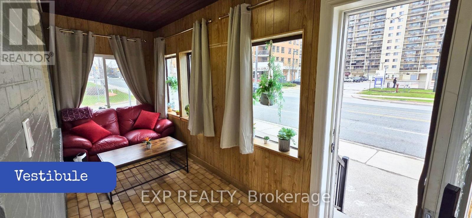 A living room with a red couch and a window overlooking a street.
