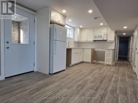 A kitchen with white cabinets and a refrigerator.