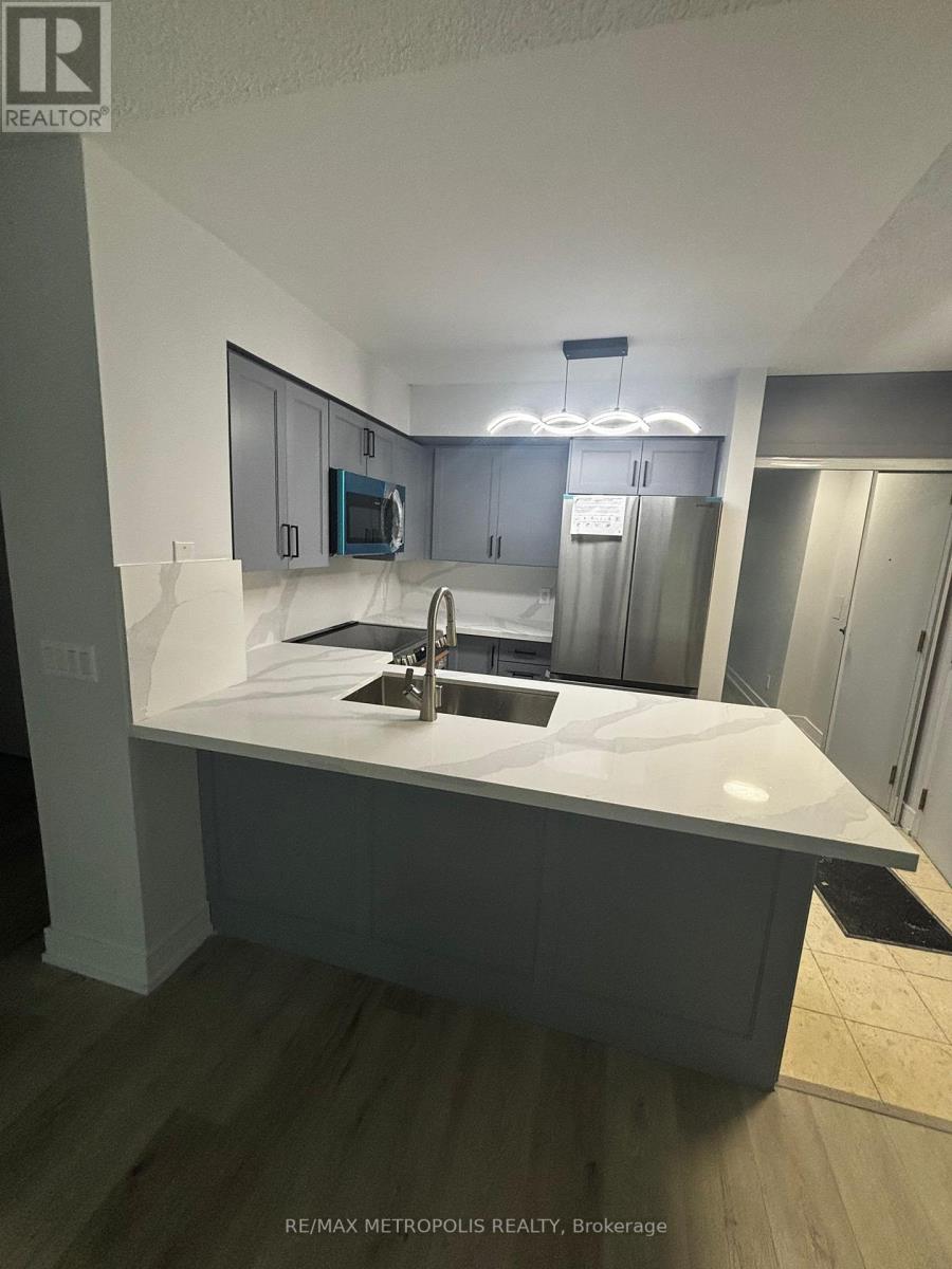 A modern kitchen with a white countertop and grey cabinets.