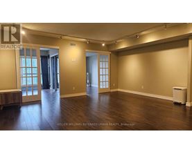 A spacious room with wood flooring and a large window.