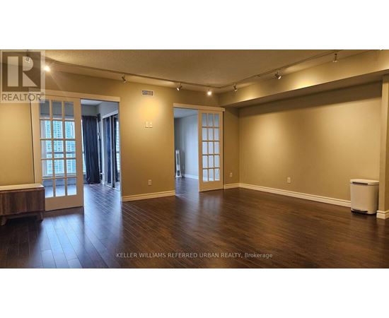 A spacious room with wood flooring and a large window.