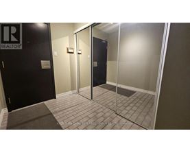 A hallway with a glass door and a black door with a Realty sign on it.