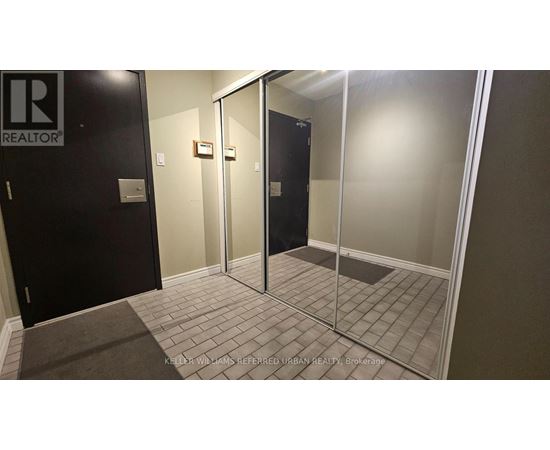 A hallway with a glass door and a black door with a Realty sign on it.