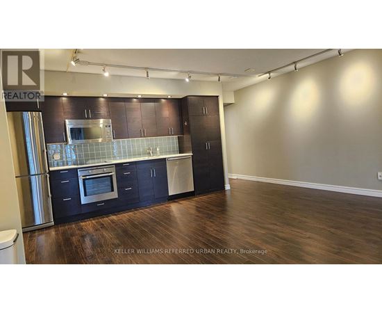 A kitchen with dark wood cabinets and a stainless steel refrigerator.