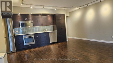 A kitchen with dark wood cabinets and a stainless steel refrigerator.